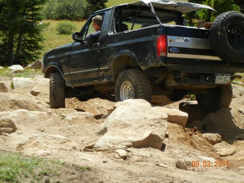 1996 Ford Bronco - 1996 Ford Bronco tackling a challenging off-road course with large rocks.