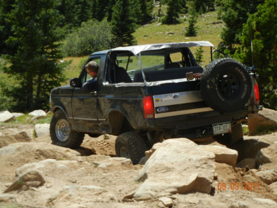 Black 1996 Ford Bronco driving over rocks on a trail