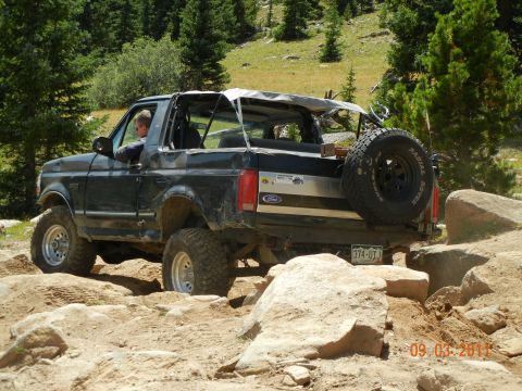 1996 Ford Bronco - This black Ford Bronco, likely from the early to mid-1990s, is shown tackling a challenging off-road course.