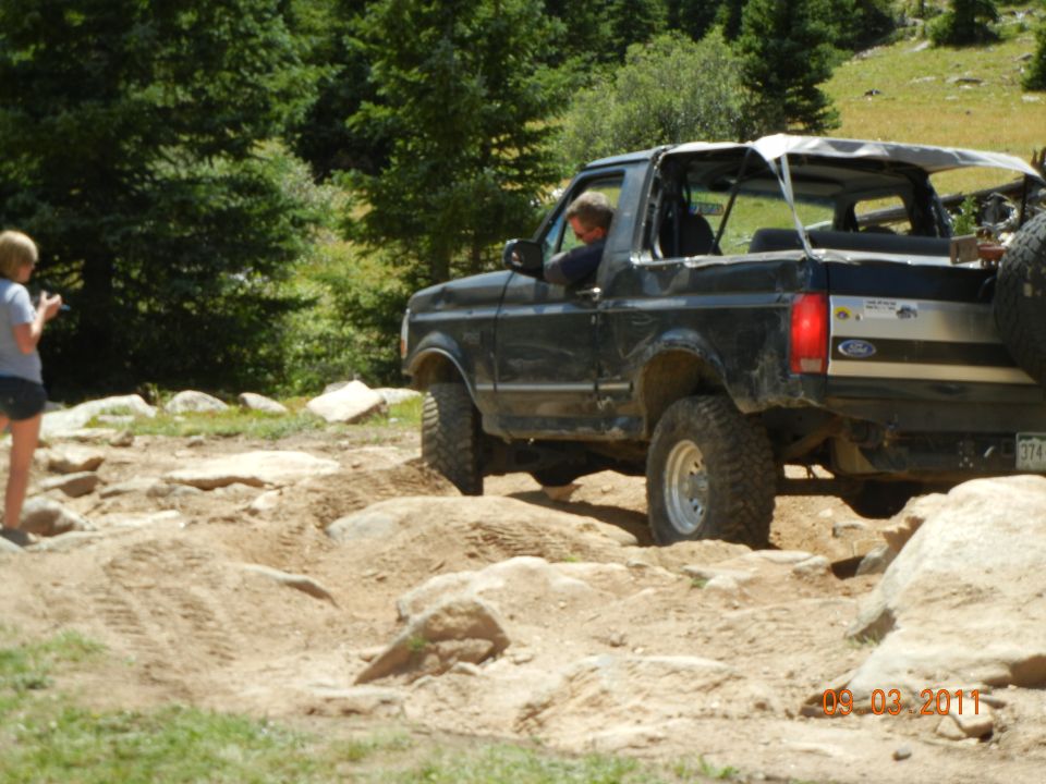 Black 1996 Ford Bronco convertible off-roading on a rocky trail