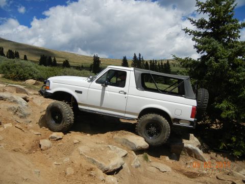 1996 Ford Bronco - This 1996 Ford Bronco is shown off-roading on a rocky mountain trail under a cloudy sky.