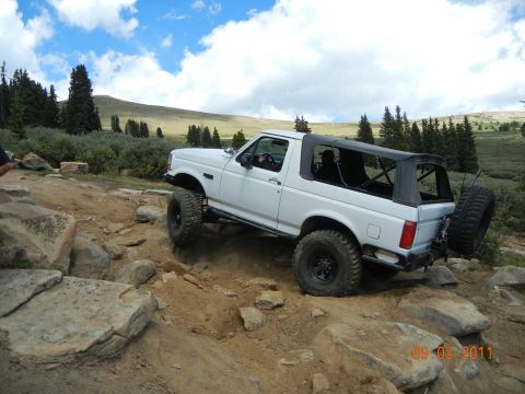 1996 Ford Bronco - This 1996 Ford Bronco navigates a challenging rocky terrain under a partly cloudy sky.