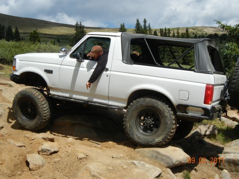 1996 Ford Bronco - 1996 Ford Bronco tackling a challenging off-road trail with large rocks.