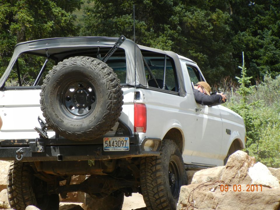 White Ford Bronco on rocky trail, driver leaning out window