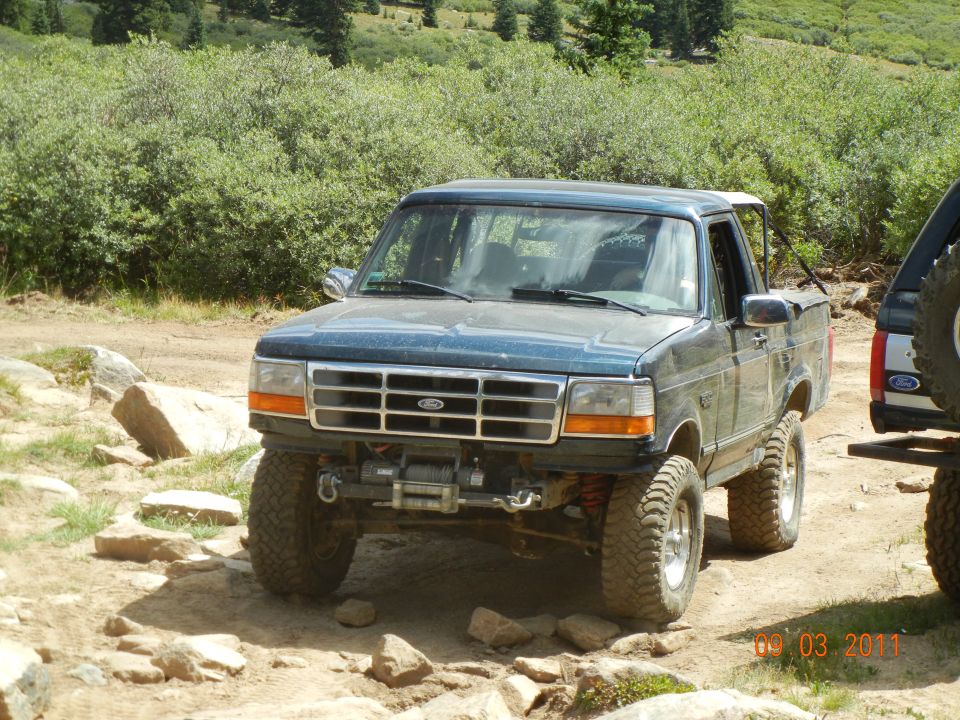 Dark blue 1995 Ford Bronco with winch and off-road tires on a rocky trail
