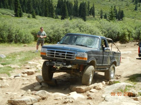 1996 Ford Bronco - 1996 Ford Bronco tackling a challenging off-road course on a sunny day.