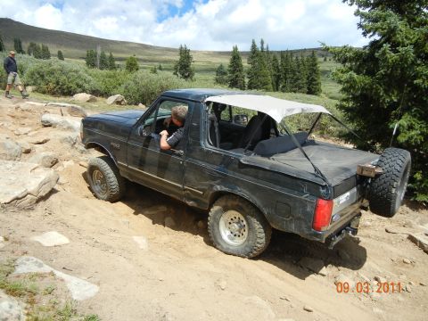 1996 Ford Bronco - 1996 Ford Bronco navigating a challenging off-road trail with rocky terrain.
