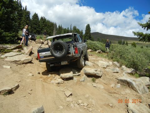 1996 Ford Bronco - A Ford Bronco tackles a challenging off-road trail with spectators watching.