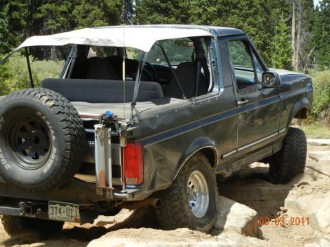 1996 Ford Bronco - This 1996 Ford Bronco is navigating a rocky trail with its white soft top deployed.