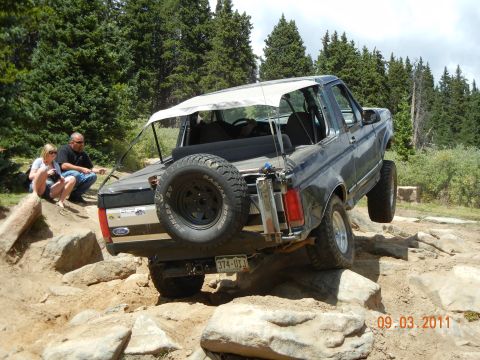 1996 Ford Bronco - A Ford Bronco navigates a rocky trail with two people watching.