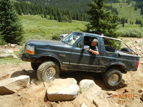 1996 Ford Bronco - A man drives a 1996 Ford Bronco over rocks on a mountain trail.