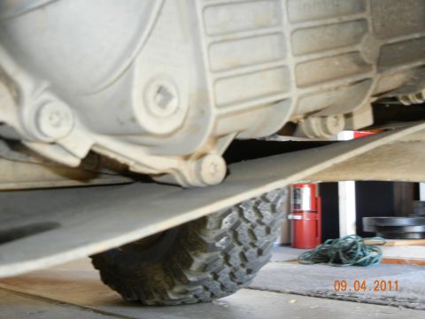 1996 Ford Bronco - Close-up of the underside of a vehicle, focusing on the transmission and tire.