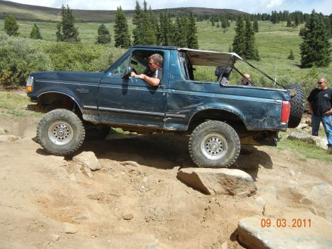 1996 Ford Bronco - A 1996 Ford Bronco tackles a challenging rocky trail with a driver and passenger visible.