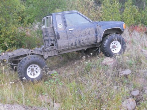 1986 Ford F-150 - This heavily modified pickup truck, likely from the 1980s, is shown in a side profile, positioned on uneven terrain.