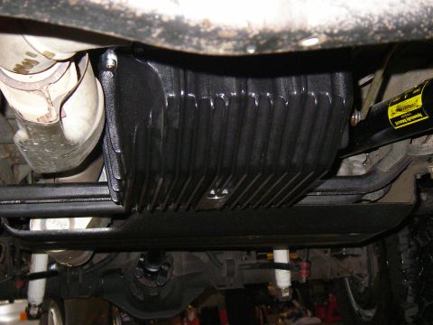 1990 Ford Bronco - Underside view of a vehicle's transmission pan and exhaust components, a yellow warning label.