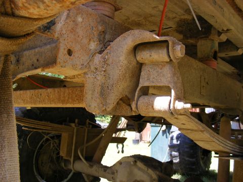 1978 Ford Bronco - A close-up view of the heavily rusted undercarriage and suspension system of an older vehicle.