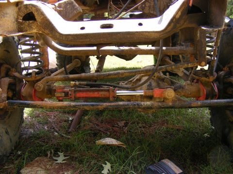 1978 Ford Bronco - Close-up view of the front axle and steering system of a heavily modified off-road vehicle.