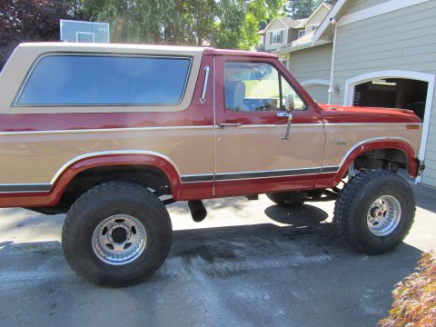 1984 Ford Bronco - Side view of a lifted 1984 Ford Bronco with two-tone paint and aftermarket wheels.