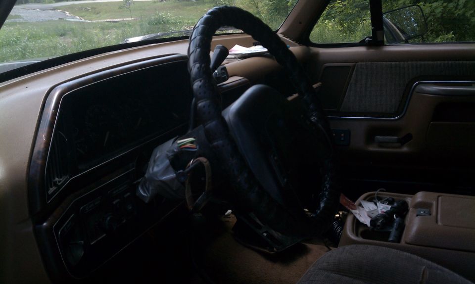 Tan Ford Bronco interior with black steering wheel and exposed wiring under the steering column