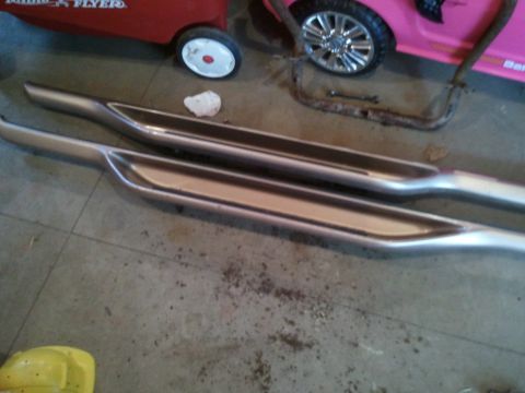 1996 Ford Bronco - Two chrome running boards are laid out on a concrete floor.
