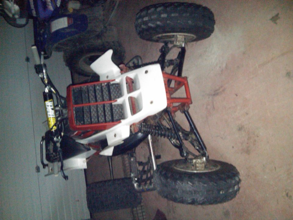 White and red sport quad ATV with knobby tires in a garage setting