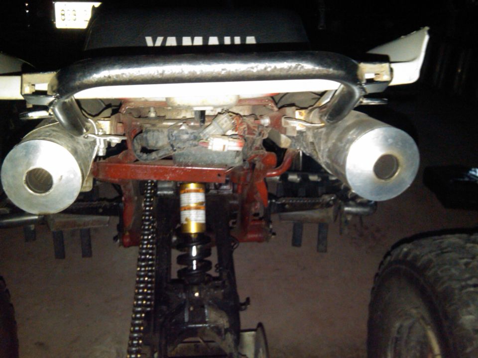 Rear of a Yamaha ATV showing dual exhaust mufflers and rear suspension