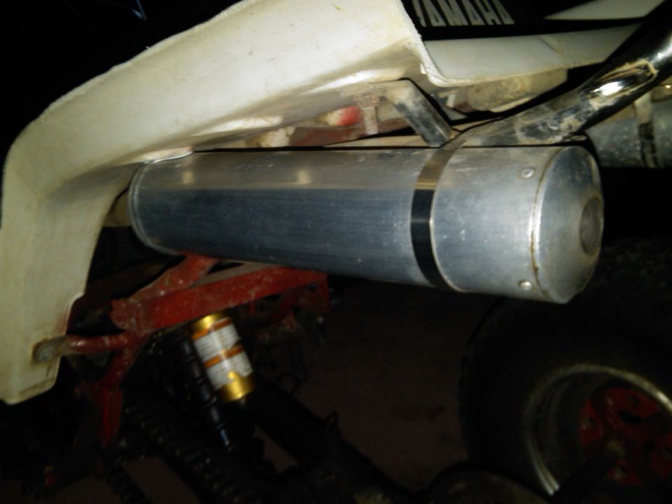 Aluminum exhaust muffler mounted on a white-and-red Yamaha ATV