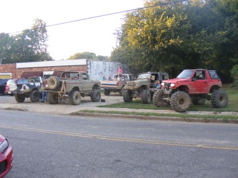 1978 Ford Bronco - A collection of modified off-road vehicles are parked together on a sunny day.
