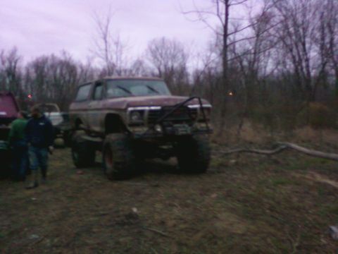 1978 Ford Bronco - A lifted 1978 Ford Bronco sits in a dirt lot with trees in the background.