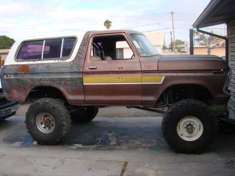 1979 Ford Bronco - This modified 1979 Ford Bronco features a lifted suspension, large off-road tires, and a visible roll cage inside the cabin.