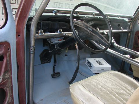 1979 Ford Bronco - The interior of a vehicle is shown, a custom roll cage, beige seat, and a box of CROW parts.
