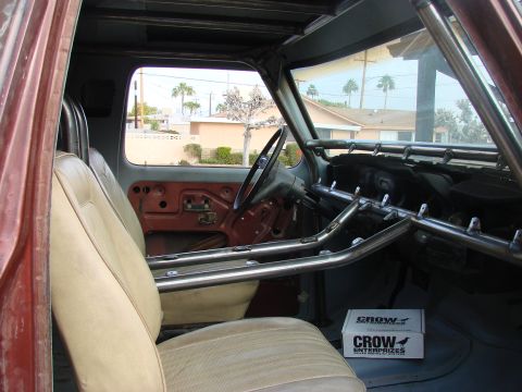 1979 Ford Bronco - The interior of a vehicle is shown, a custom roll cage and tan upholstery. A box from Crow Enterprises is visible on the floor.