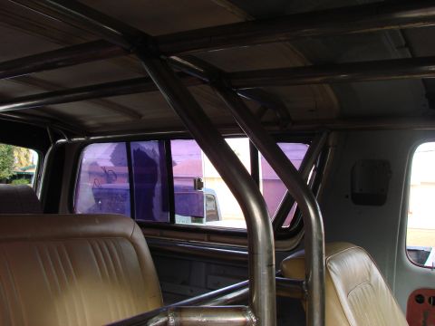 1979 Ford Bronco - Custom roll cage structure inside a vehicle with tan upholstery and purple tinted windows.