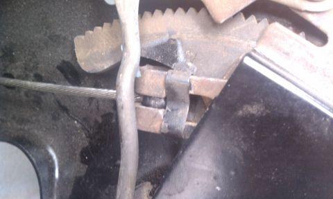 1979 Ford Bronco - Detail of a vehicle's parking brake assembly, showing the cable and ratchet mechanism.