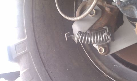 1979 Ford Bronco - A close-up view of a vehicle's parking brake mechanism, showing its components and connection to the wheel assembly.