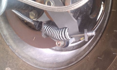 1979 Ford Bronco - Detail of a vehicle's parking brake mechanism, showing the spring and cable components.