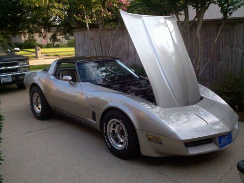 1982 Chevrolet Corvette - A silver 1982 Chevrolet Corvette is parked outside with its hood open, revealing the engine bay.