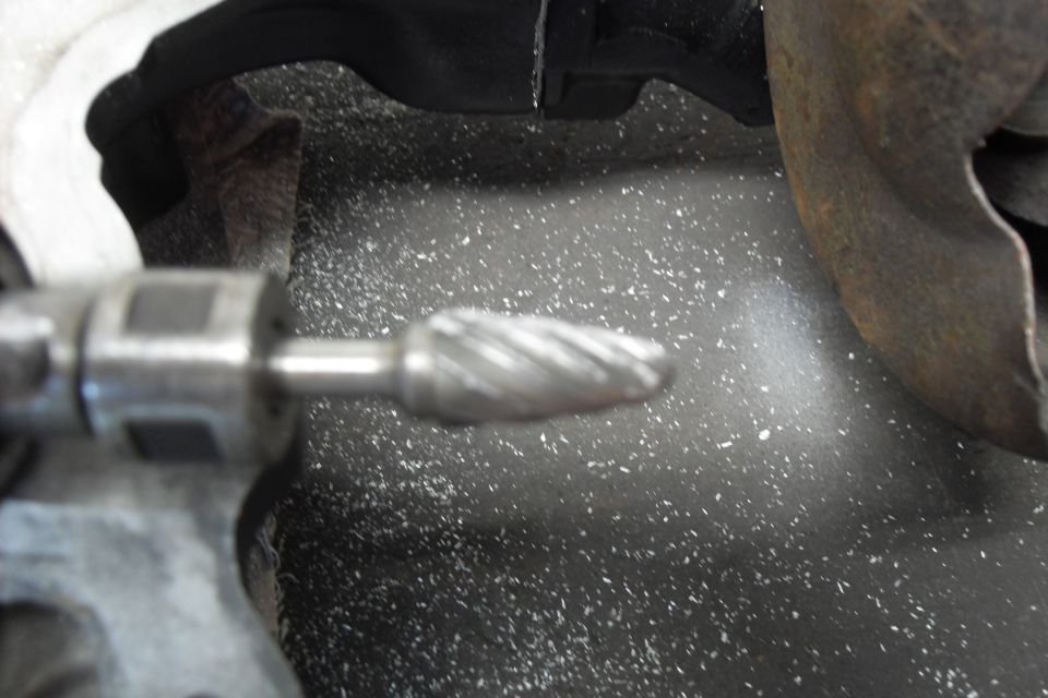 Rotary burr tool grinding metal with debris scattered