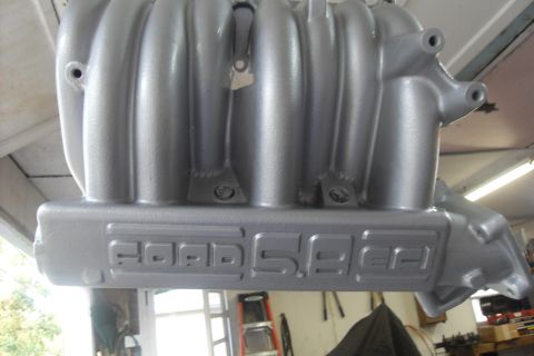 1997 Ford Ranger - A silver intake manifold with 'Ford 5.0' embossed on its side is shown hanging in a workshop.