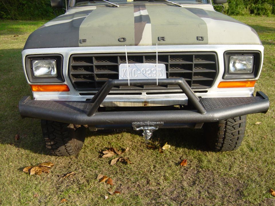 Front view of a 1979 Ford Bronco with a camouflage hood and a black aftermarket bumper