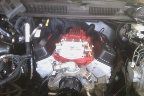 1996 Chevrolet Camaro - Close-up view of a modified engine bay, a prominent red intake manifold and associated plumbing.