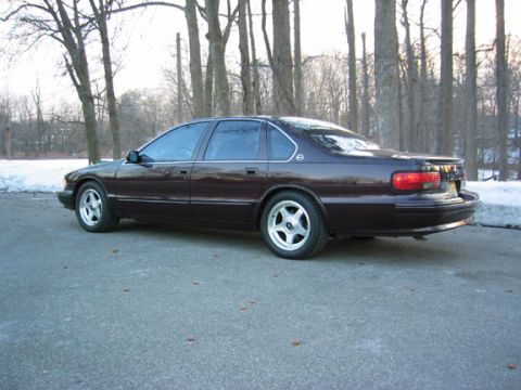 1996 Ford Crown Victoria - A dark sedan is parked on an asphalt surface with trees and snow in the background.