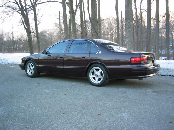 Dark maroon full-size four-door sedan, rear three-quarter view with snow