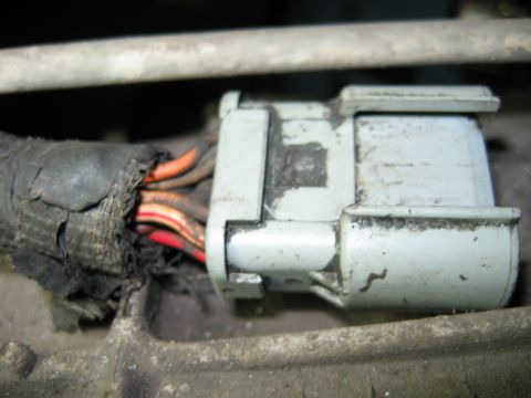 1992 Ford Bronco - A close-up view of a damaged wiring harness connector, revealing exposed orange and red wires.