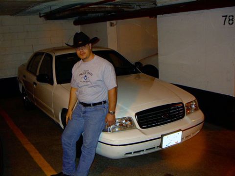 1999 Ford Crown Victoria - A man in a cowboy hat poses with a white 1999 Ford Crown Victoria in a parking garage.