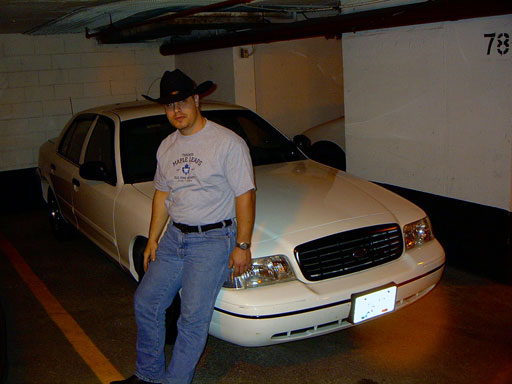 White 1999 Ford Crown Victoria front 3/4 view with a man leaning on it