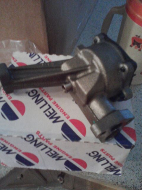 1989 Ford Bronco - A metal oil pump is shown resting on a box labeled Melling Engine Parts.