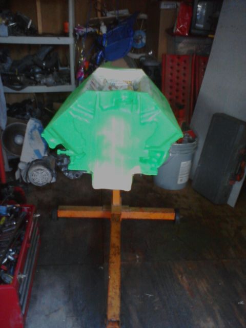 1989 Ford Bronco - An engine block, painted green, is mounted on a stand in a cluttered garage setting.