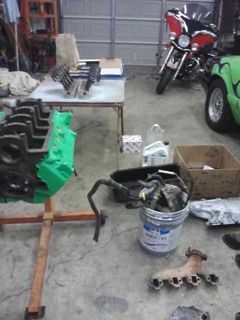 1989 Ford Bronco - Garage scene with engine parts, a motorcycle, and other automotive components.