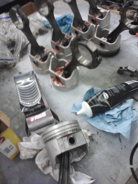 1989 Ford Bronco - Engine parts, including pistons and connecting rods, are laid out on a surface with assembly lube and new piston rings.